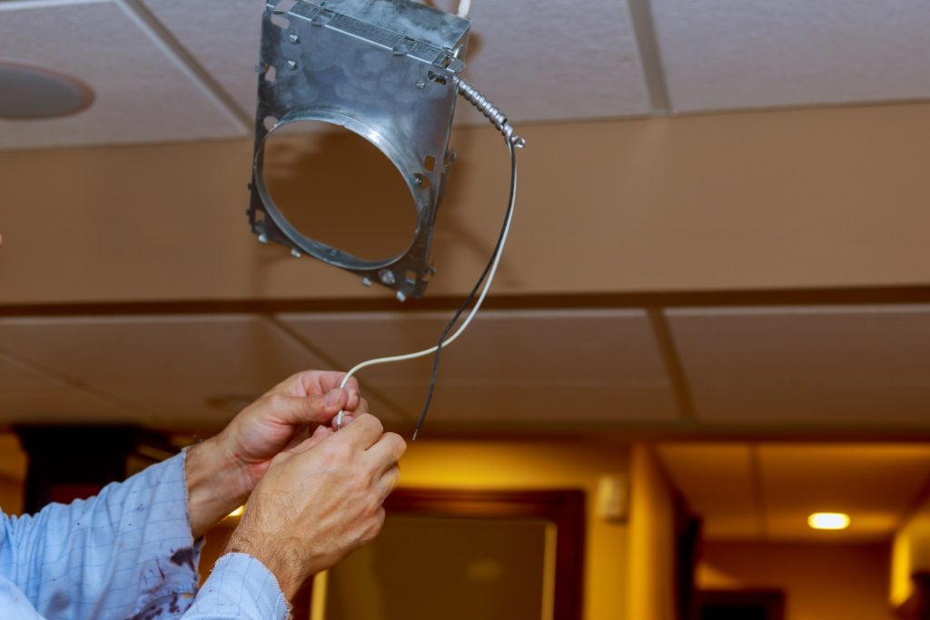 Electrician is installing and connecting a lamp to a ceiling.