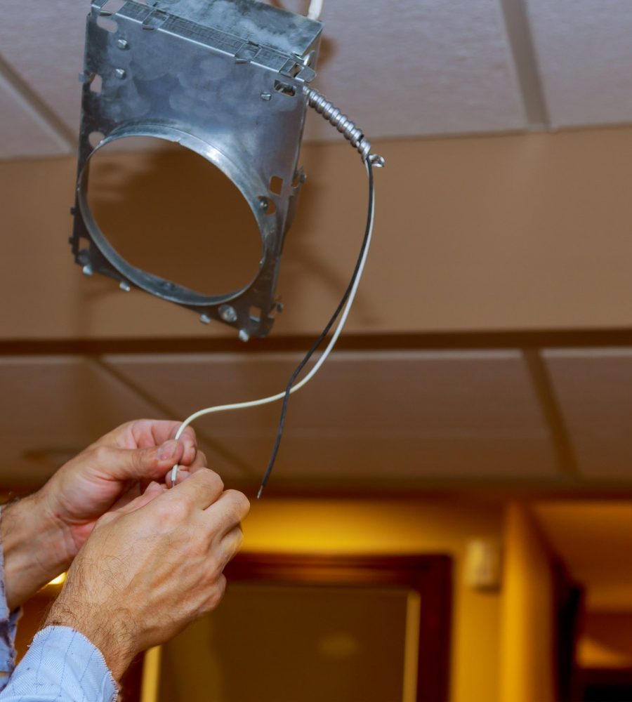 Electrician is installing and connecting a lamp to a ceiling.